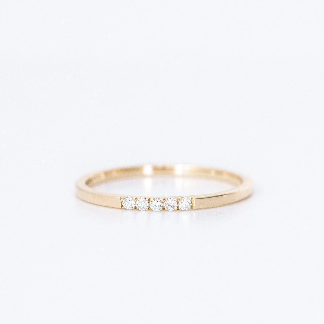 thin diamond wedding band with 5 small diamonds in yellow gold